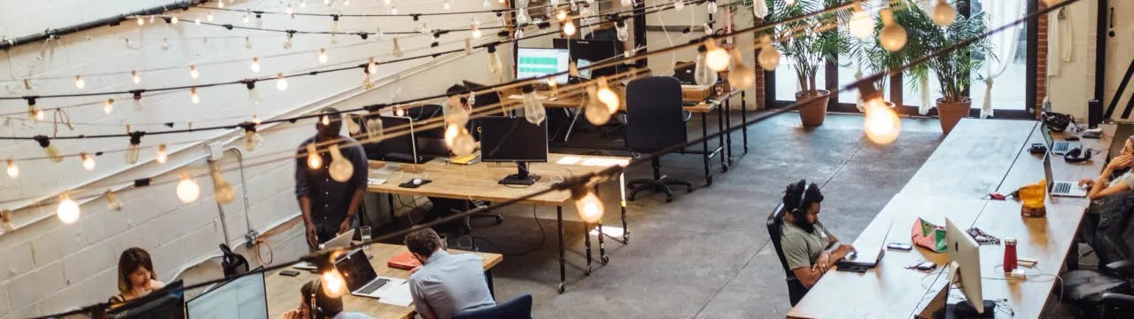 people sitting in front of computer monitors in a coworking space